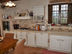 Una cocina con estufa a gas, horno y lavabo, con armarios y ventana.