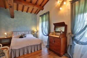 Un dormitorio con una cama de madera, un aparador, un espejo y una mesita de noche con una lámpara.