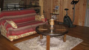 Una sala de estar con un sofá, una mesa de centro, un aspirador y una estantería.
