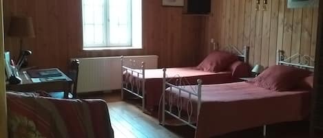 A cabin with a wooden interior, two beds, a table, and a chair.