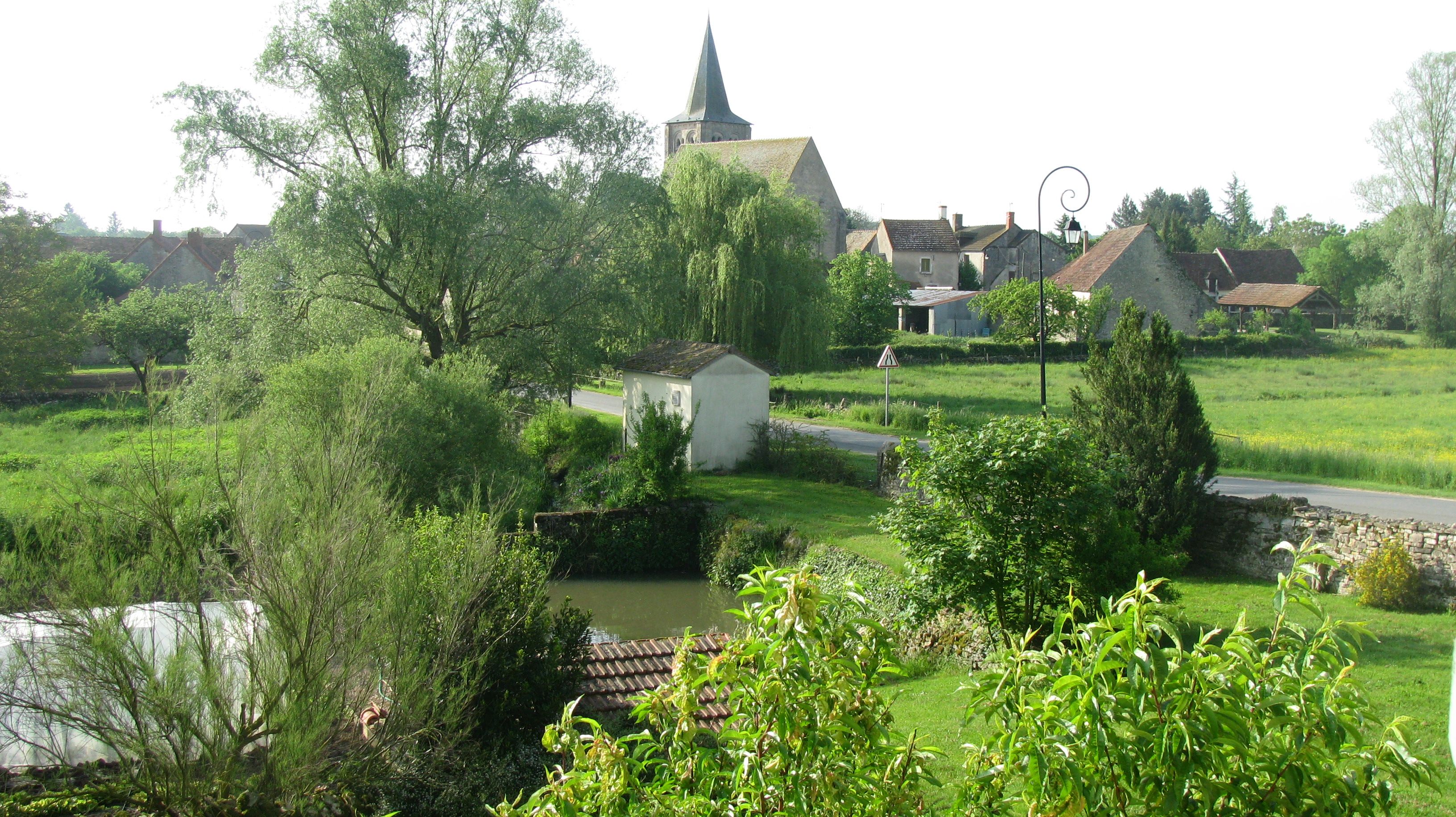 Un paysage rural avec une église, un petit bâtiment blanc et une route.