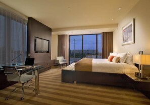 Ein Hotelzimmer mit Bett, Schreibtisch, Stuhl und großen Fenstern.