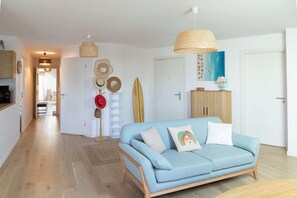 Un salon avec un canapé bleu clair, un meuble en bois et une planche de surf.