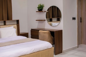 A bedroom with a bed, a desk, a chair, a mirror, and a shelf with a plant. - Spacious unique 3 bedroom apartment (Lagos)
