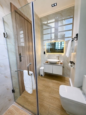 A modern bathroom with a glass shower enclosure, a white sink, and a toilet. - Spacious unique 3 bedroom apartment (Lagos)