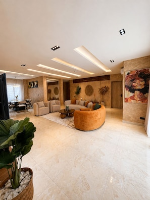 A spacious living area with a sofa, coffee table, and a potted plant. - Spacious unique 3 bedroom apartment (Lagos)