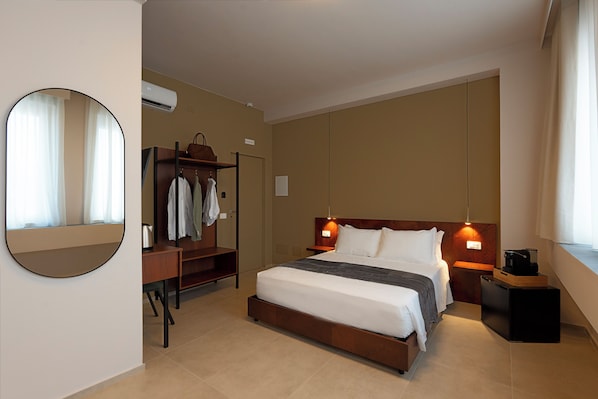 Una habitación de hotel con cama, armario, espejo y mesita de noche.
