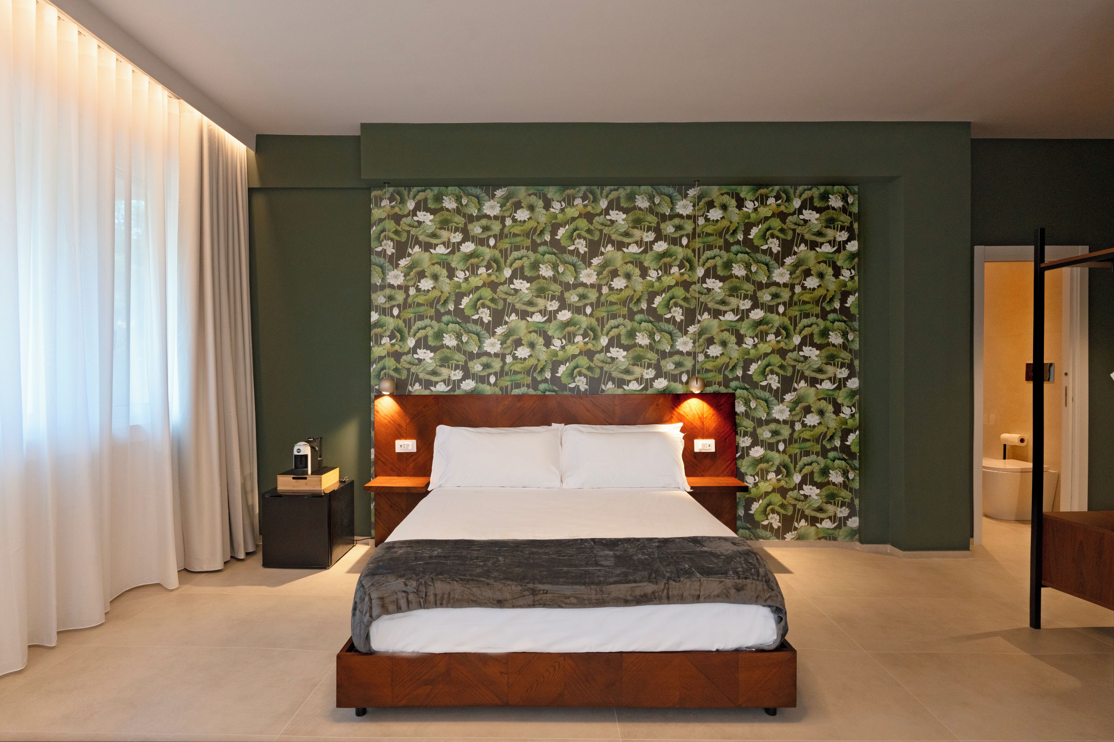 Un dormitorio moderno con cabecera de madera, una cama grande y un papel tapiz floral verde.