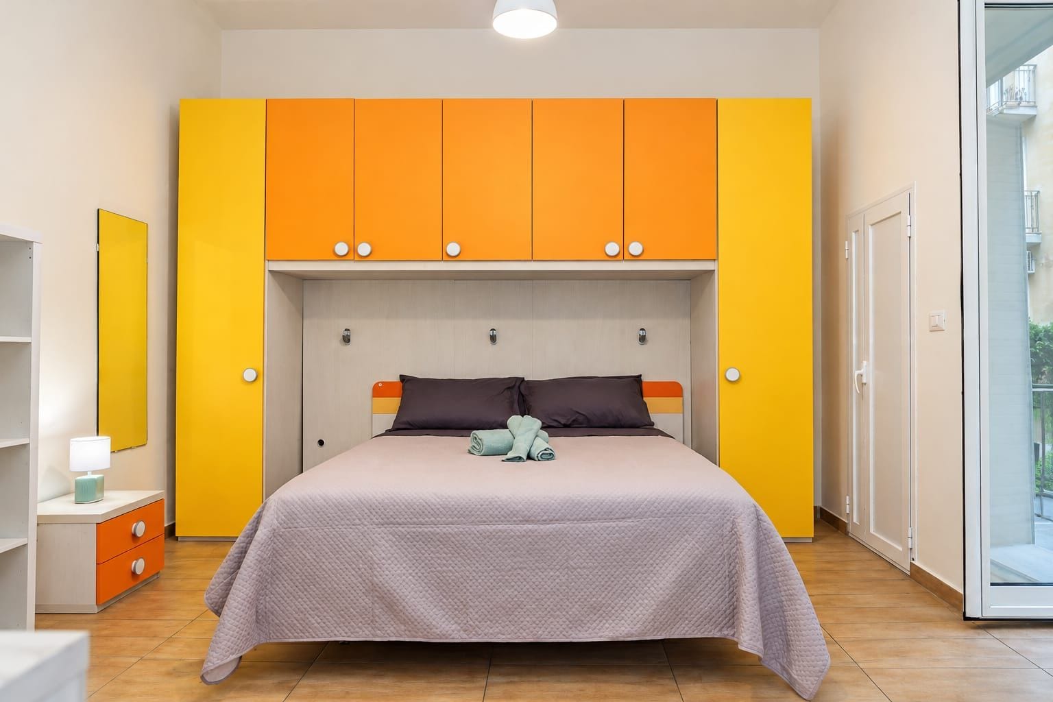 A bedroom with a bed, a nightstand, and a window.