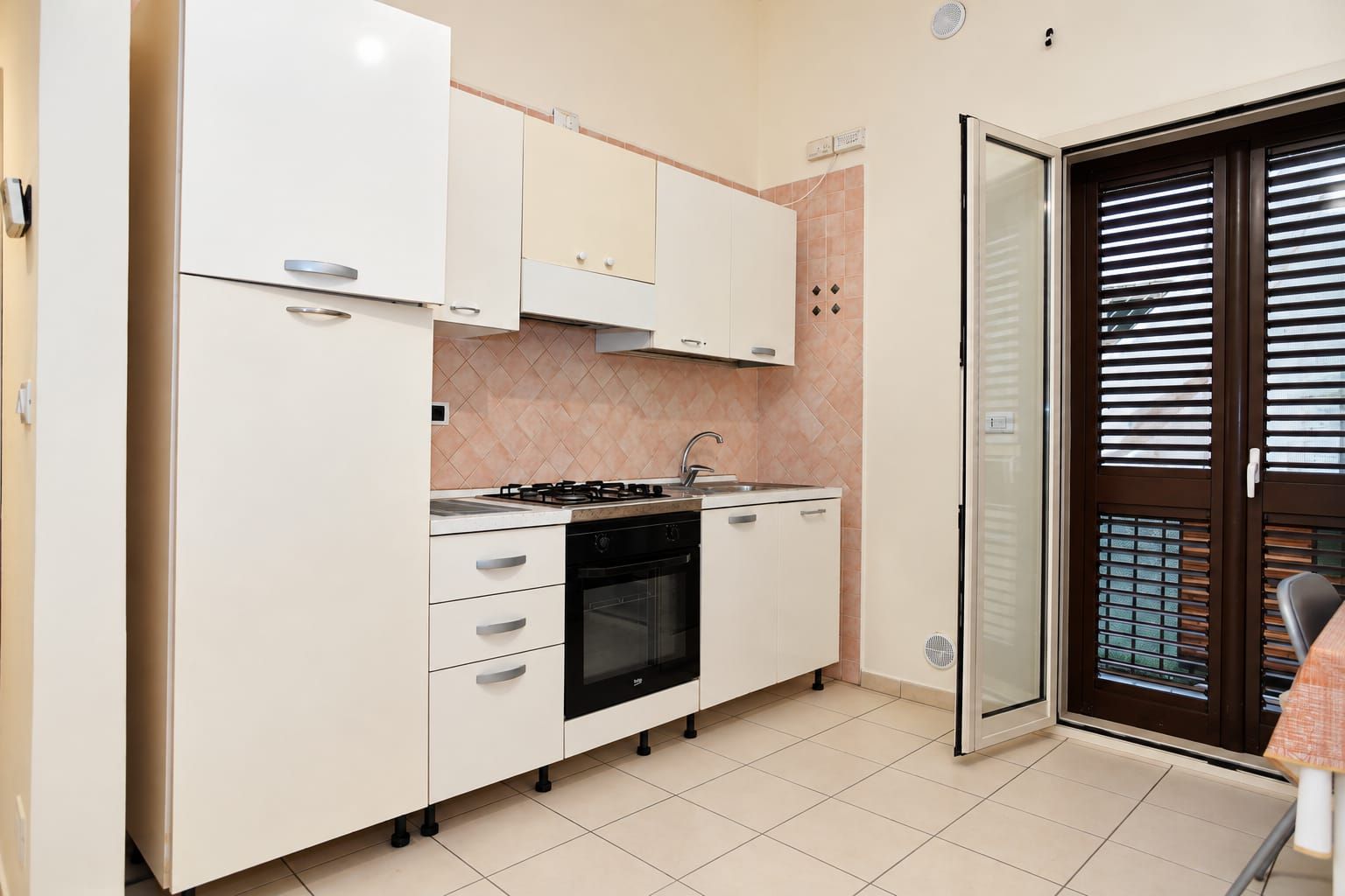 A compact kitchen with white cabinets, a gas stove, and a built-in oven.