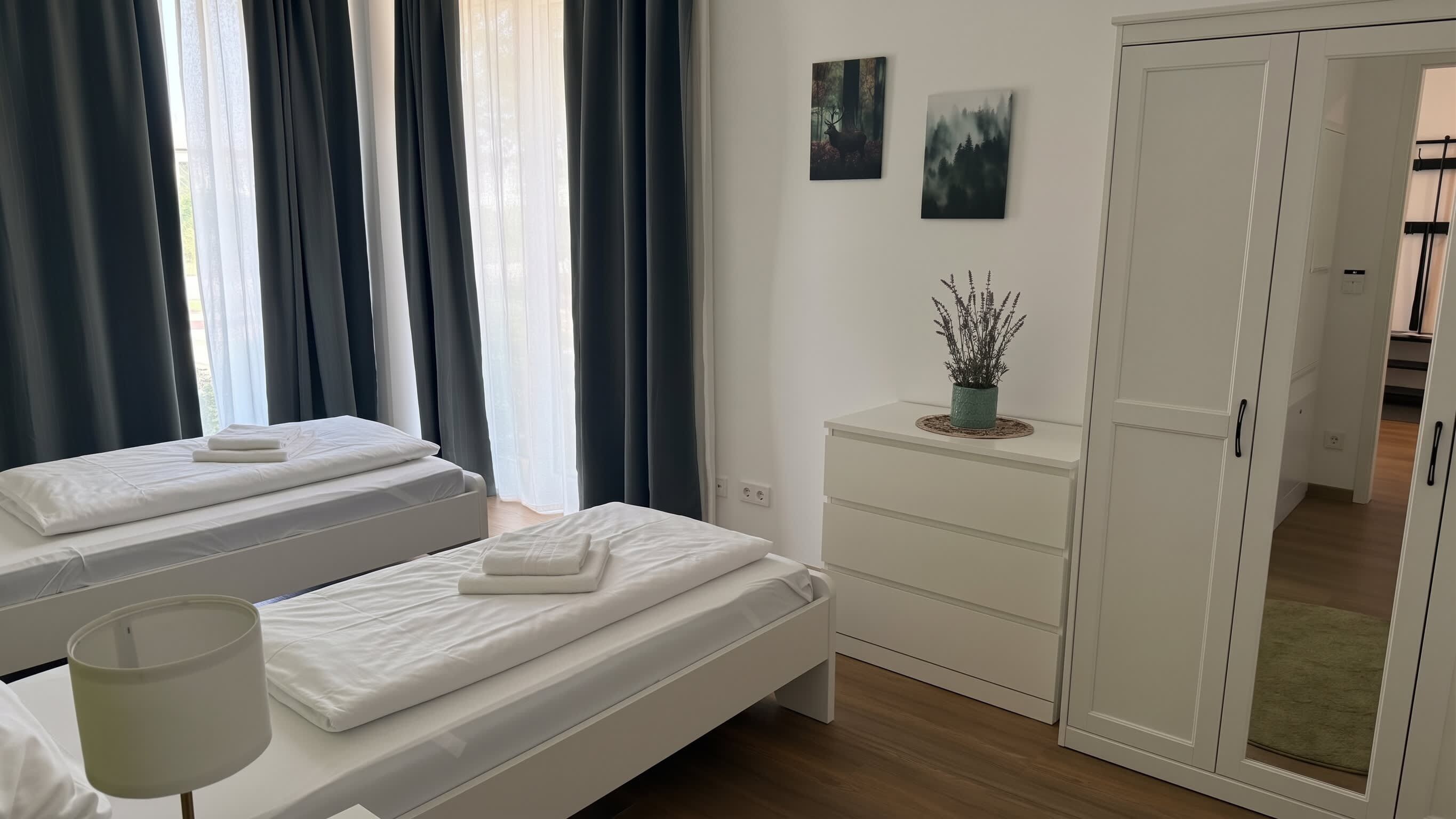 Ein Hotelzimmer mit zwei Betten, einem Nachttisch, einem Schminktisch und einem Kleiderschrank.