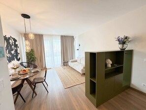 Ein modernes Wohnzimmer mit Essbereich, einer Couch und einem grünen Schrank.