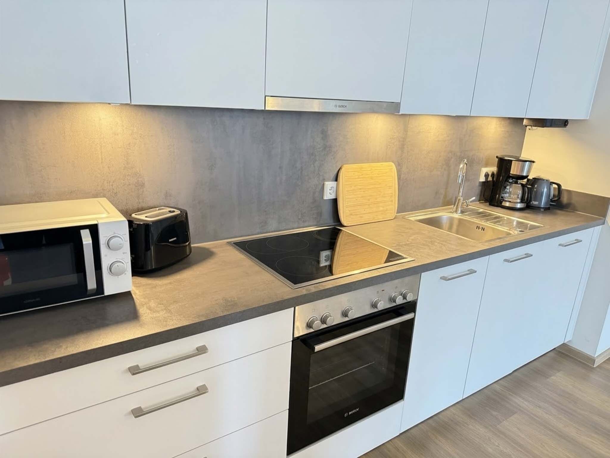 Eine moderne Küche mit Mikrowelle, Toaster, Herd, Spüle und Kaffeemaschine.