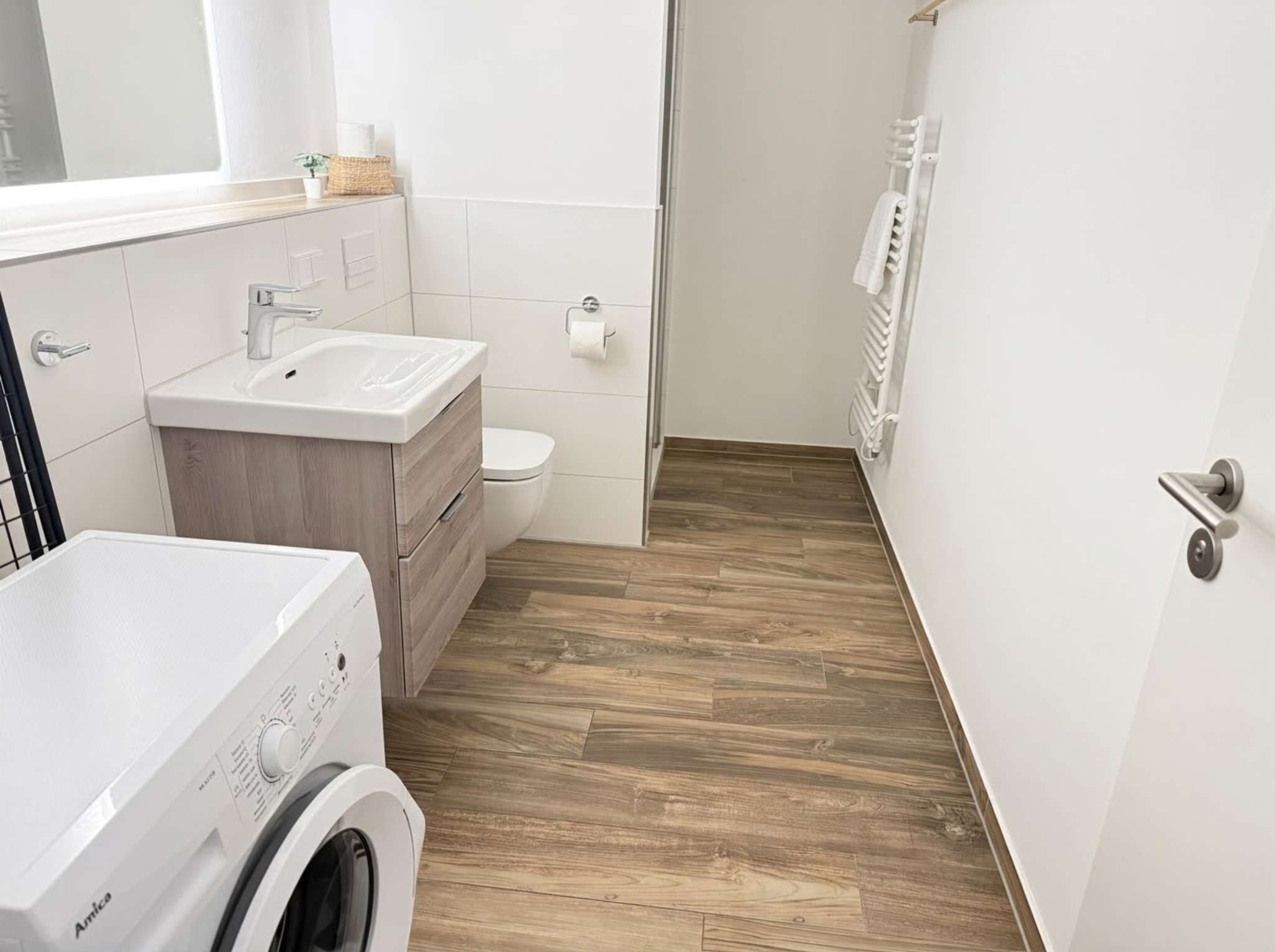 Ein modernes Badezimmer mit Waschmaschine, Waschbecken und Toilette.