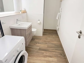 Ein modernes Badezimmer mit Waschmaschine, Waschbecken und Toilette.