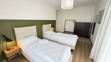 Ein Hotelzimmer mit zwei Betten, einem Nachttisch mit Lampe, einer Hängelampe und einem Kleiderschrank.