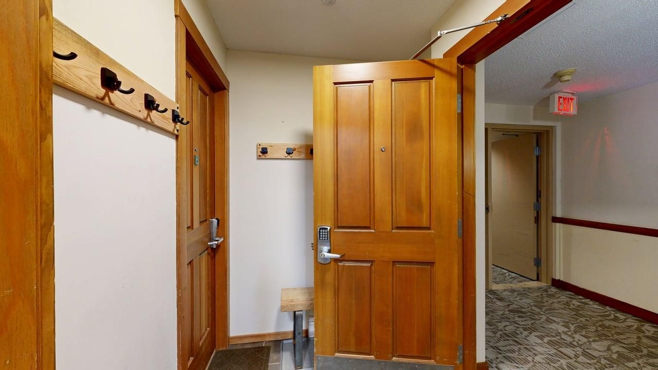 A hallway with wooden doors, a bench, and an exit sign.