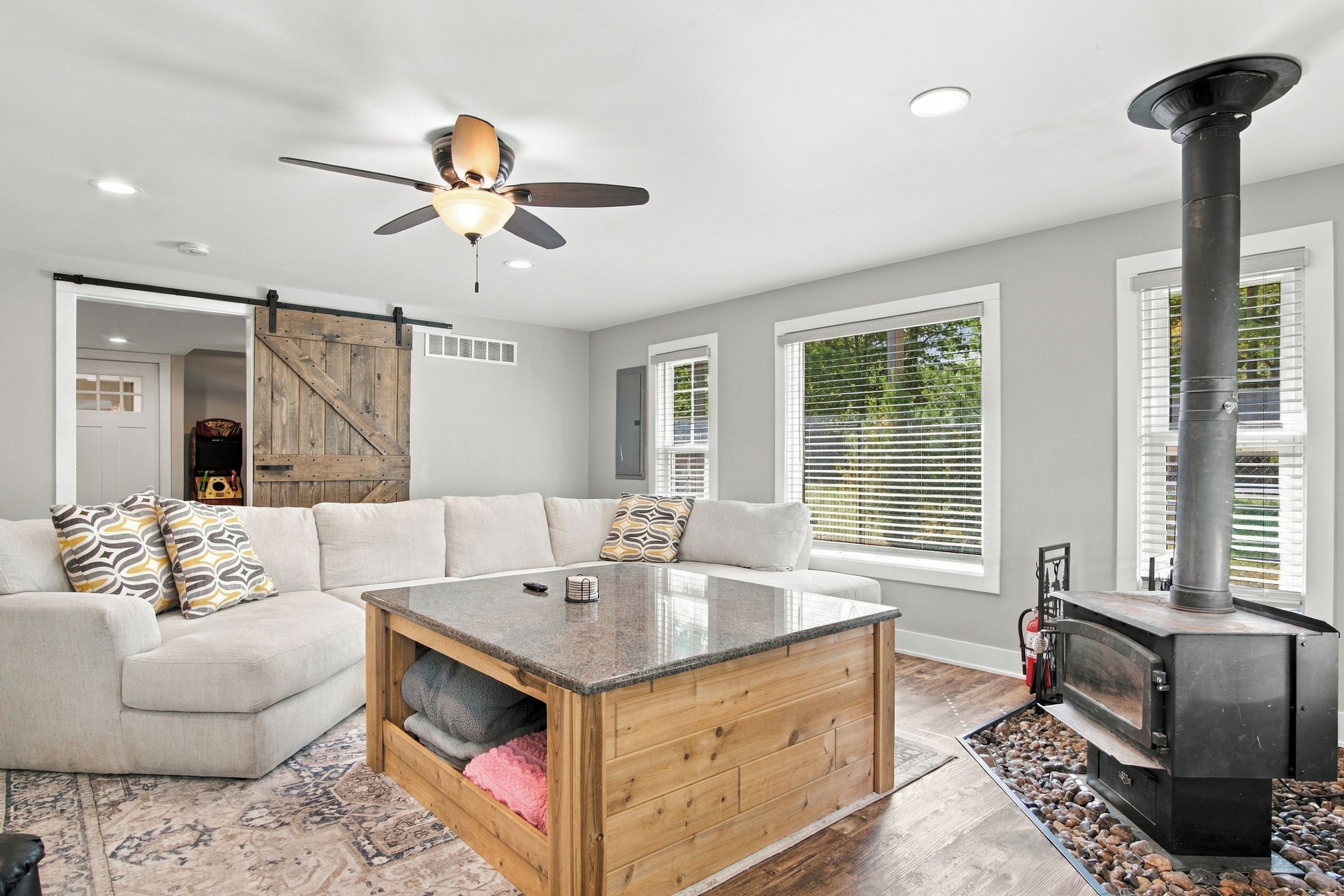 A modern living room with a sofa, a coffee table, a fireplace, and a ceiling fan.