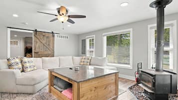 A modern living room with a sofa, a coffee table, a fireplace, and a ceiling fan.