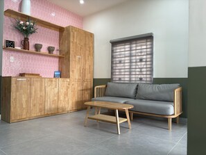 Un salón moderno con un armario de madera, un sofá gris y una pequeña mesa de madera.