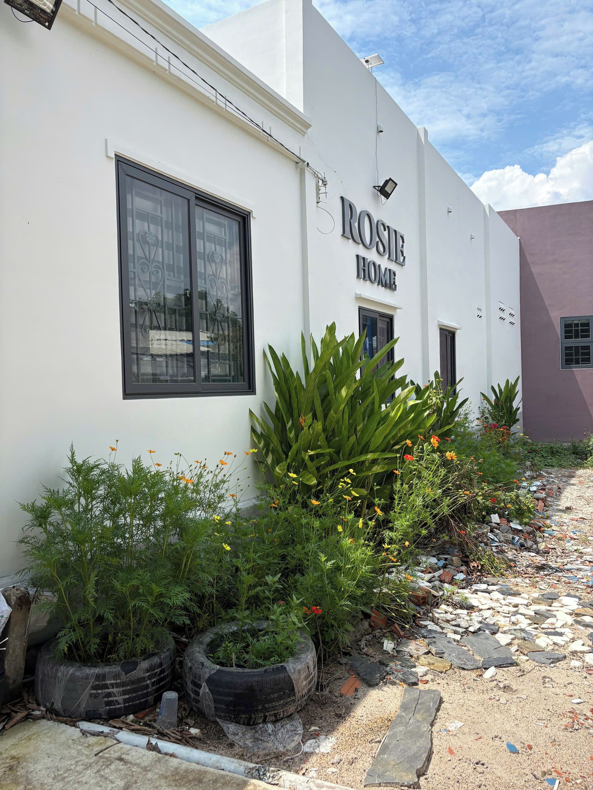 Un edificio con un letrero que dice 'ROSIE HOME' y una ventana con una reja decorativa.
