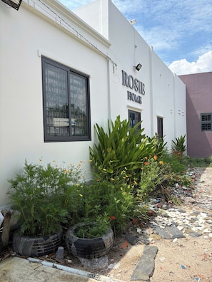 Um edifício com uma placa indicando 'ROSIE HOME' e uma janela com grade decorativa.