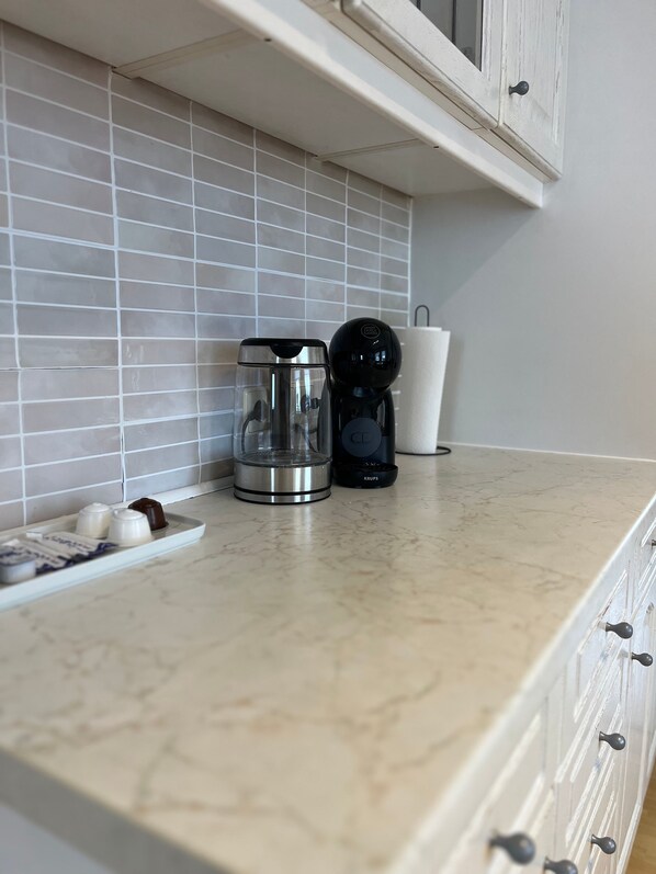 Eine Küchenarbeitsplatte mit einer Kaffeemaschine, einer Glas-Kaffeekanne und einer Schale mit Eiern und Schokolade.