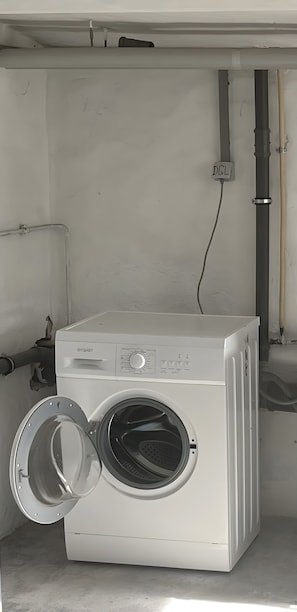 Eine Waschmaschine mit Frontlader, einer Bedienkonsole, einer Steckdose und einem Wasserzulaufrohr.