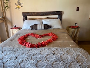 Un letto con una ghirlanda di fiori a forma di cuore, una testiera in legno e due comodini decorati con fiori rossi.