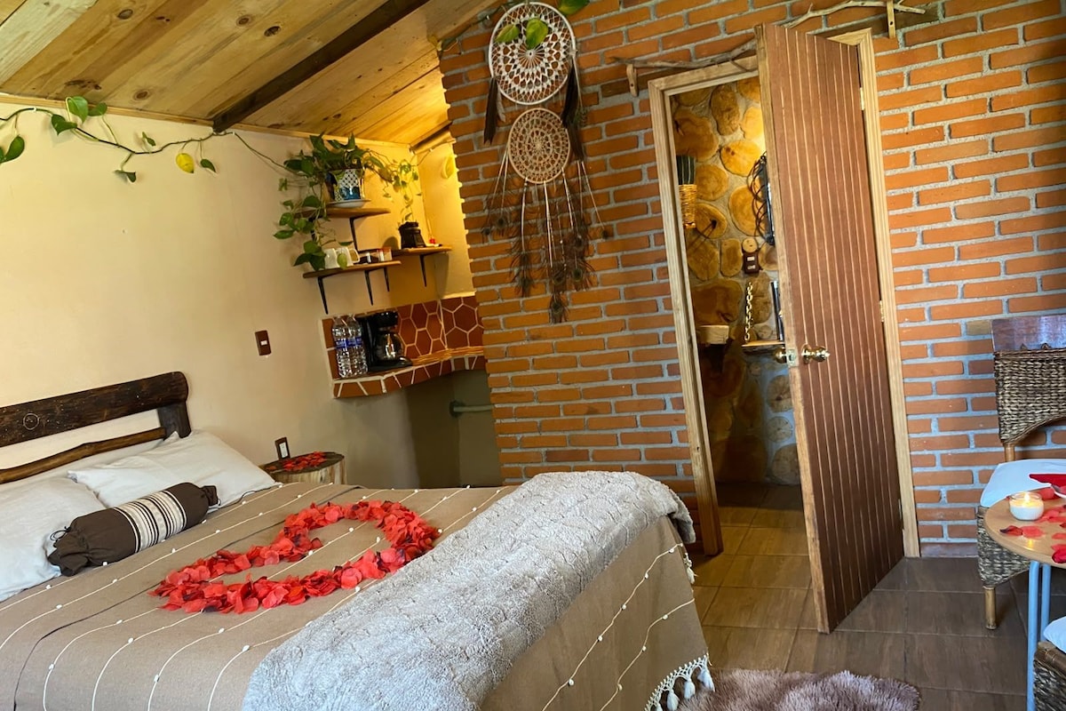 Una camera da letto accogliente con un letto, una testiera in legno, una parete in mattoni e un tavolino con una sedia.