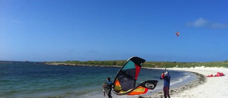 A beach with clear skies, a sandy shore, and a calm sea.