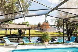 Un área de piscina exterior cubierta con sillas de descanso y una pérgola.