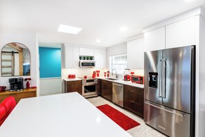 Een moderne keuken met roestvrijstalen apparatuur, een wit aanrecht en een rood vloerkleed.