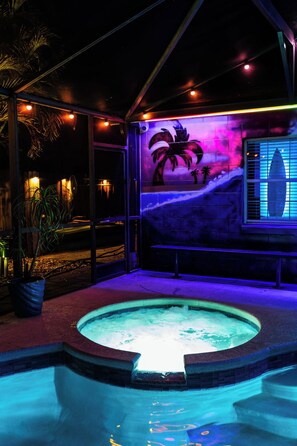Een buitenzwembad met een jacuzzi, palmbomen en een muurschildering.