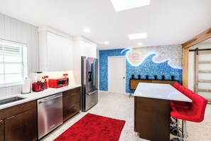 Une cuisine moderne dotée d’appareils électroménagers en acier inoxydable, d’un tapis rouge et d’une fresque murale bleue.