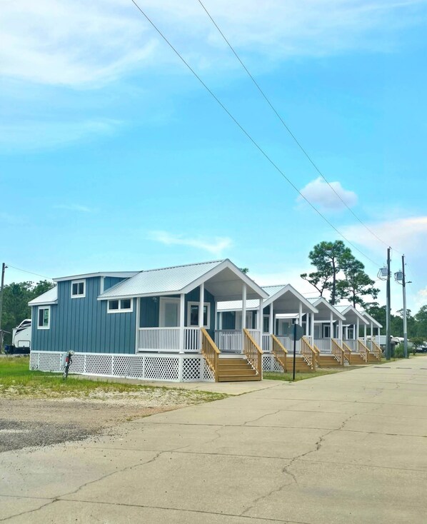 A row of mobile homes with white railings and wooden steps, connected by a shared driveway.