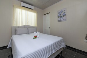 Ein Hotelzimmer mit einem Bett, einem weißen Kopfkissen, einer weißen Decke, einem wei ßen Handtuch und einem Blumenbild an der Wand.