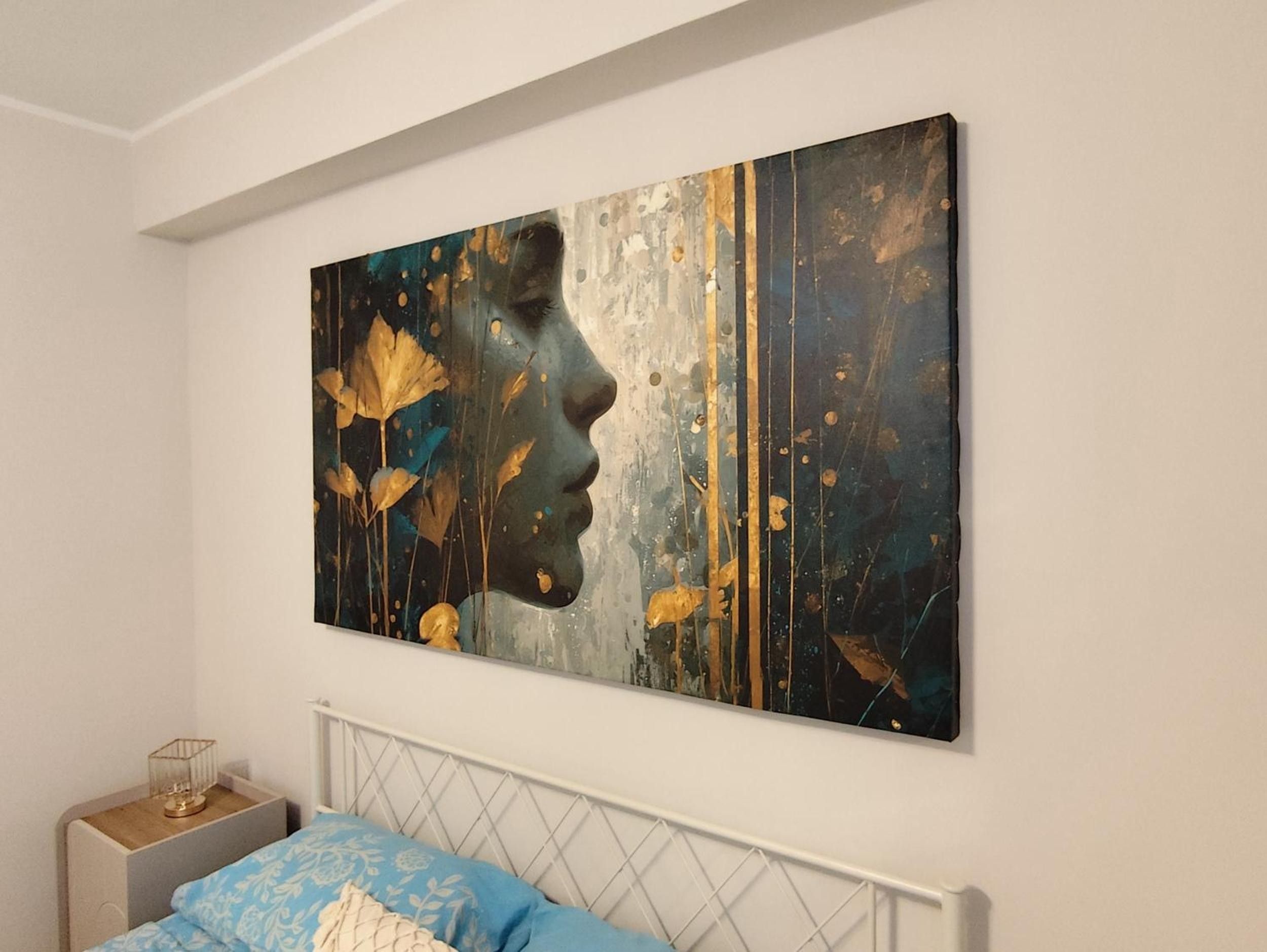A bedroom with a bed, a bedside table, and a large abstract painting on the wall.