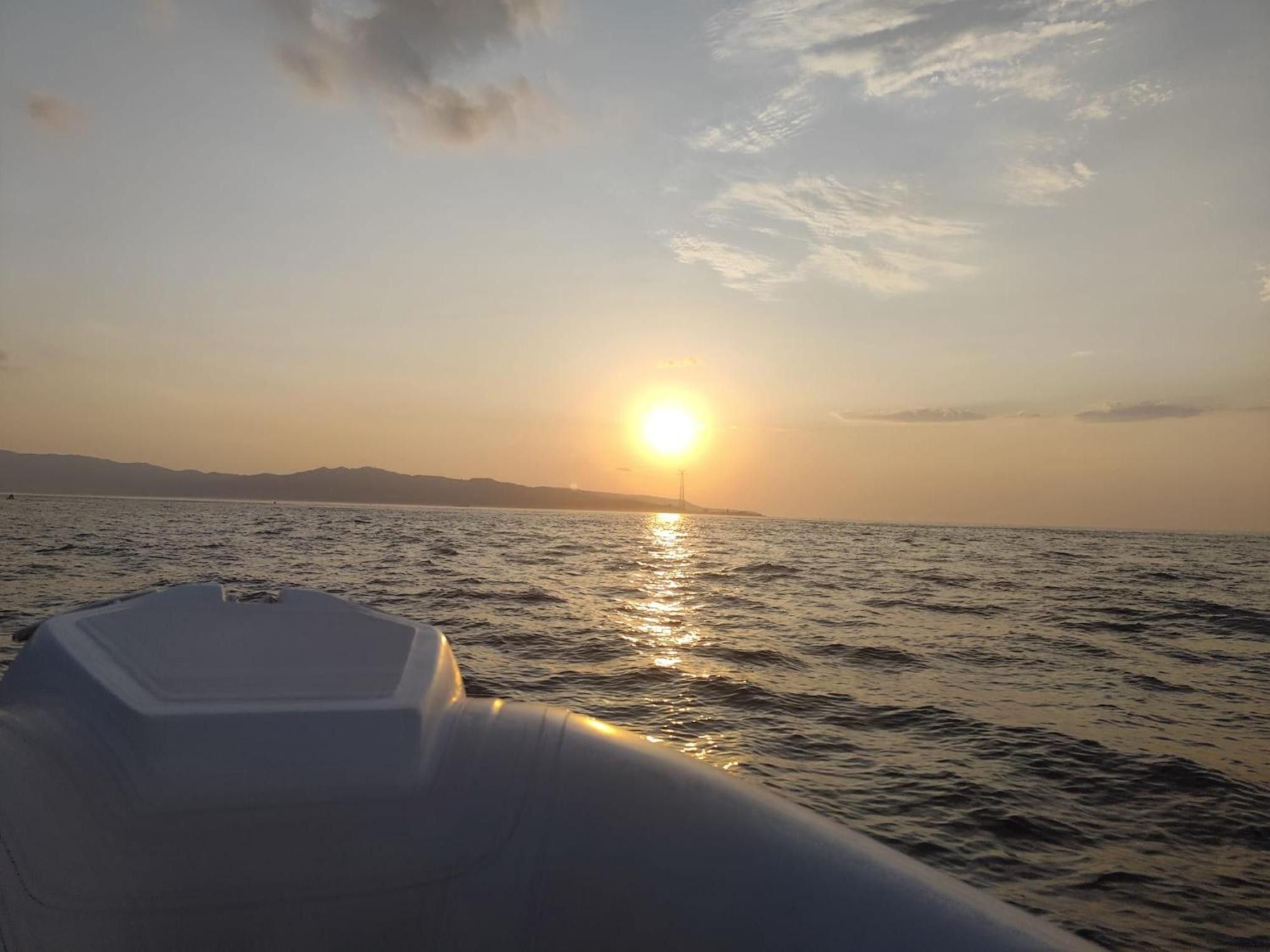A boat on calm water with a sunset in the background.
