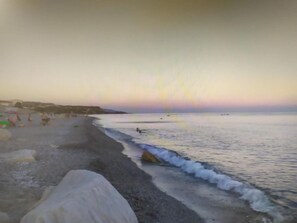 Ein Strand mit ruhiger See, blauem Himmel und ein paar Personen in der Ferne.