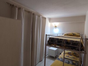 Ein Einzelstockbett mit Kopfteil, ein Nachttisch und eine Wandleuchte.