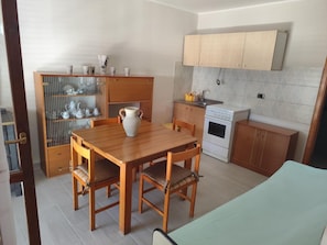 Eine kleine Küche mit Esstisch, Stühlen, Herd und Schrank.