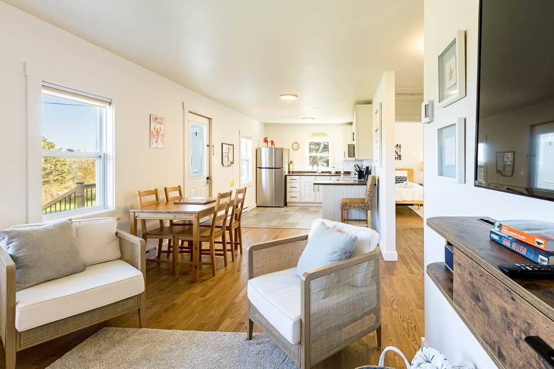 A cozy living area with a sofa, a dining table, and a kitchen in the background.