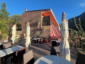 An outdoor seating area with tables and chairs, a brick wall, and a mountain backdrop. - New Listing (Ota)
