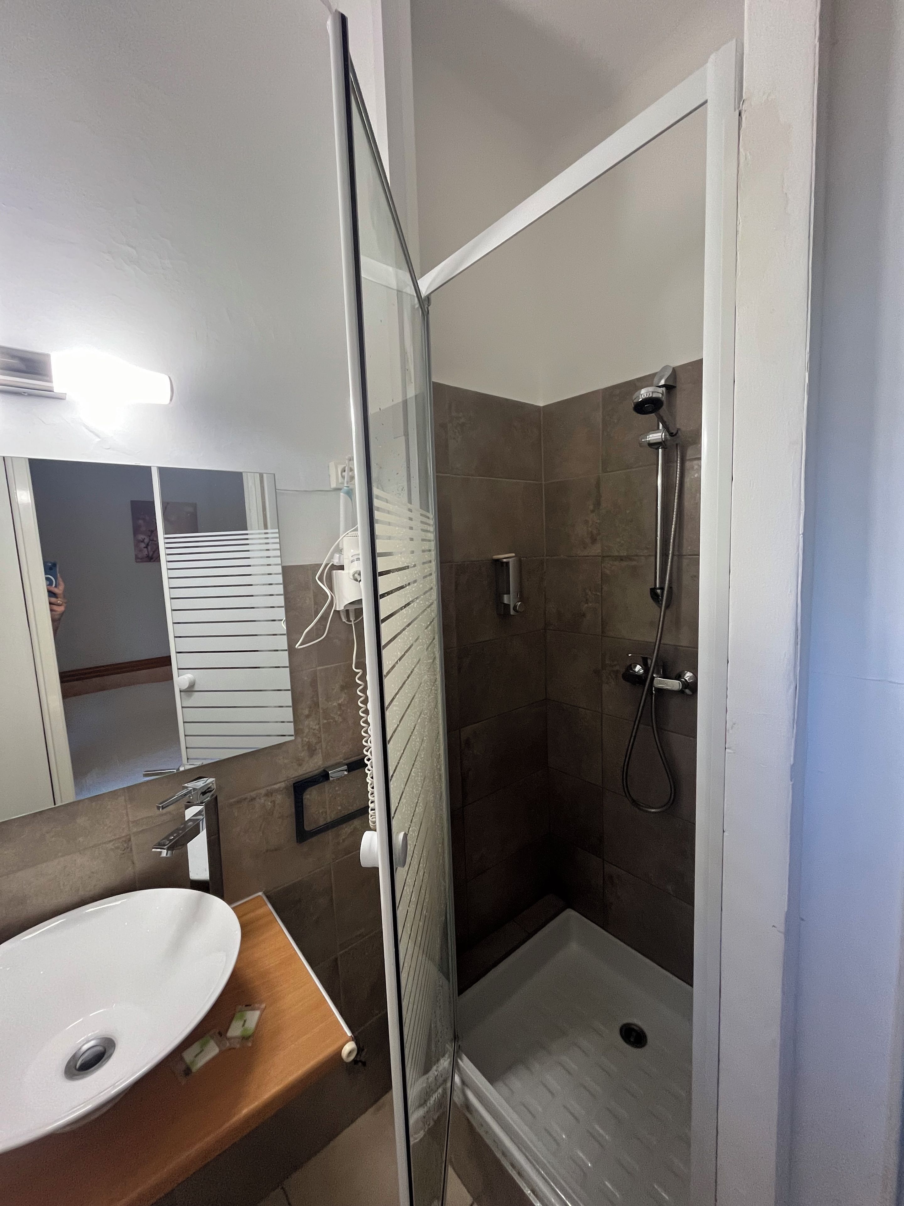 Une salle de bain avec une douche à parois de verre, un lavabo blanc et un miroir.