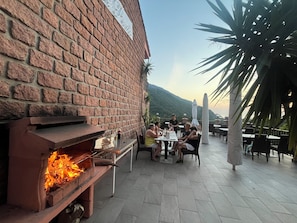 An outdoor dining area with brick walls, a brick oven, and a view of a mountain. - New Listing (Ota)