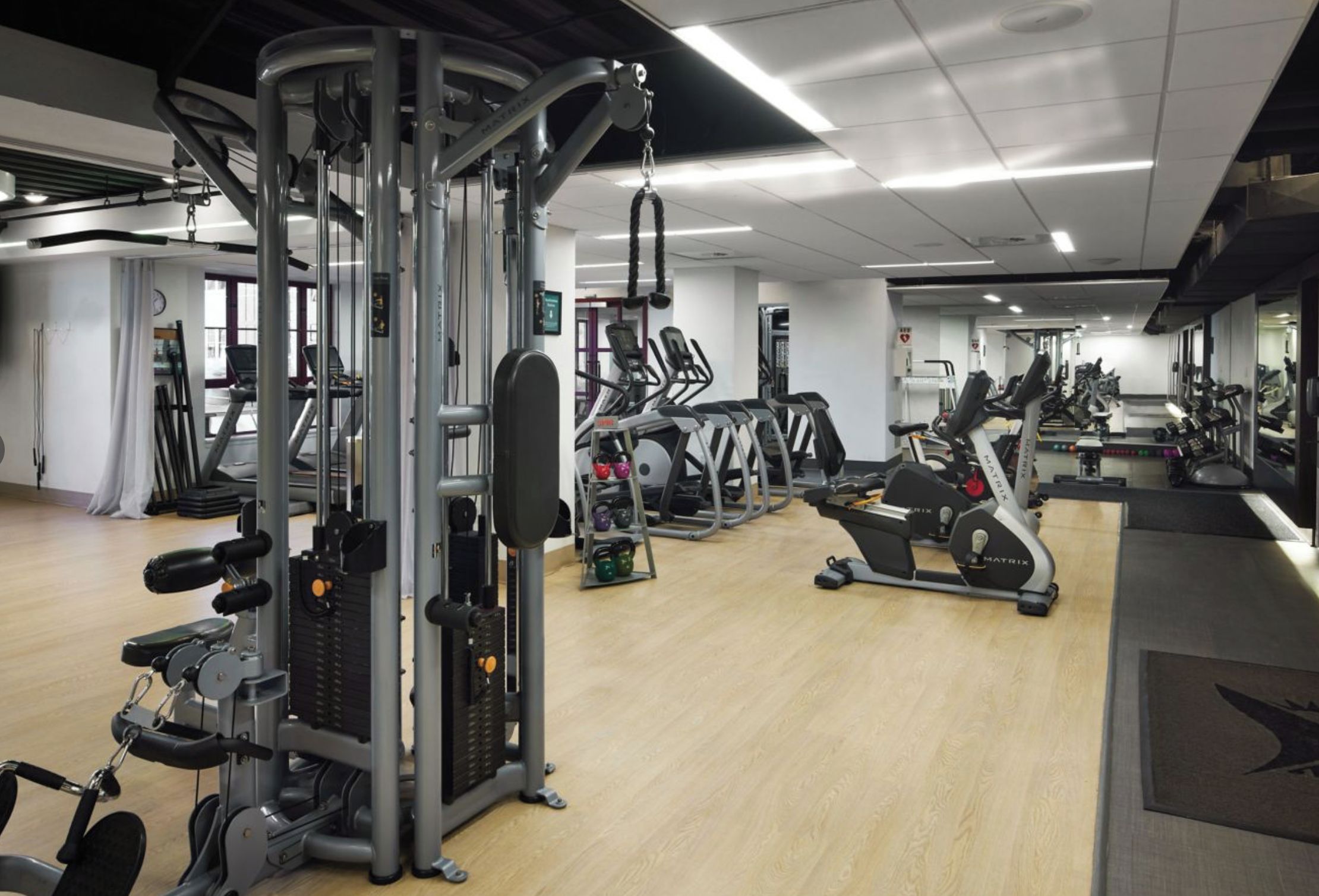 Een fitnessruimte met diverse trainingsapparaten, waaronder loopbanden, elliptische trainers en krachtstations.
