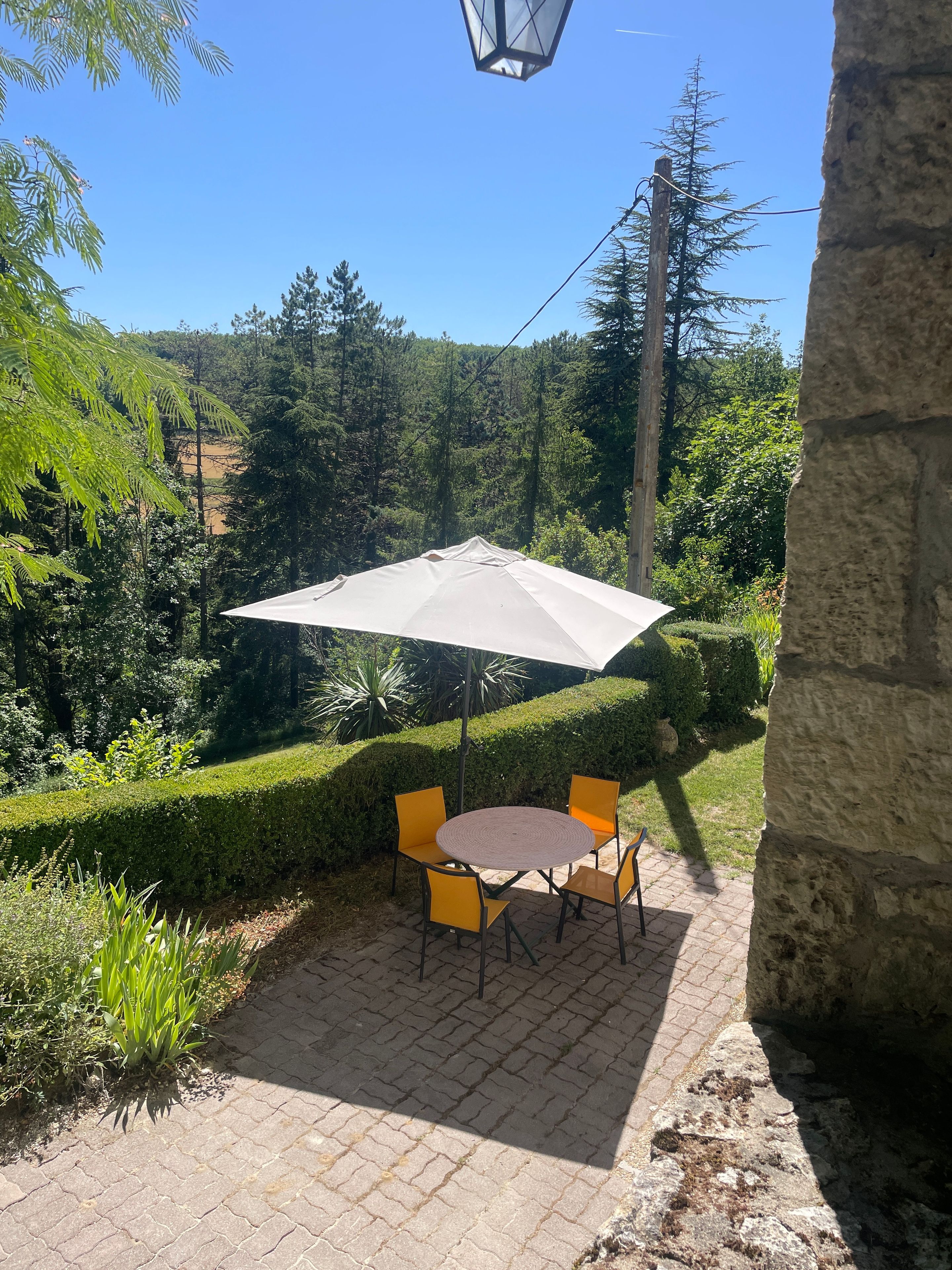An outdoor patio with a round table and chairs, an umbrella, and a stone wall.