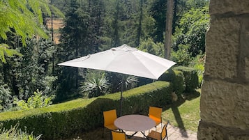 An outdoor patio with a round table and chairs, an umbrella, and a stone wall.