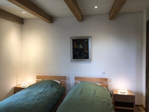 Habitación con dos camas, cabeceros de madera, un cuadro en la pared y lámparas de noche.